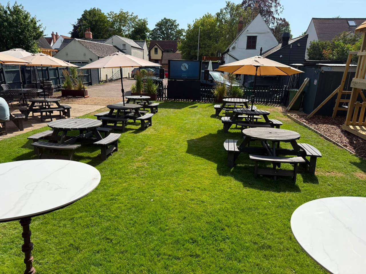 The Side Quest pub garden with picnic benches, parasols and lawn seating.